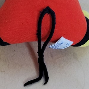 Peut inclure: Peluche rouge, noire et jaune avec une ficelle noire attach&eacute;e. Le jouet a une &eacute;tiquette blanche avec du texte noir qui dit "Disney's Winnie the Pooh".