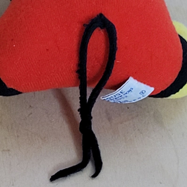 Peut inclure: Peluche rouge, noire et jaune avec une ficelle noire attach&eacute;e. Le jouet a une &eacute;tiquette blanche avec du texte noir qui dit "Disney's Winnie the Pooh".