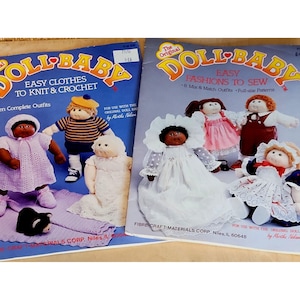 Puede incluir: Dos libros de patrones de costura para muñecas con portadas coloridas. El libro de la izquierda se titula "Doll-Baby Easy Clothes to Knit & Crochet" y presenta una muñeca con un vestido rosa de ganchillo. El libro de la derecha se titula "The Original Doll-Baby Easy Fashions to Sew" y presenta una muñeca con un vestido blanco con encaje.