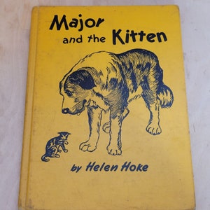 May include: A yellow book cover with black text that reads "Major and the Kitten" by Helen Hoke. The cover features a black and white illustration of a large dog and a small kitten.