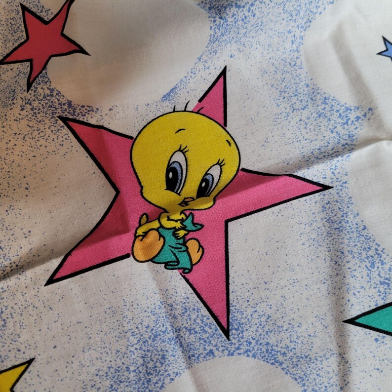 May include: A yellow cartoon bird with big eyes sits on a pink star with a white background. The bird is holding a blue and green object. The background has a blue and white speckled pattern.