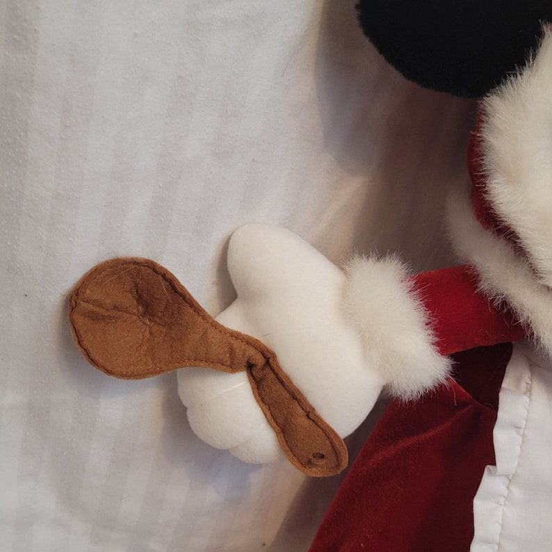 K&ouml;nnte beinhalten: Ein rotes Samt-Weihnachtskleid mit wei&szlig;em Pelzbesatz und einer braunen Filz-Santa-M&uuml;tze. Das Kleid hat einen wei&szlig;en Spitzenbesatz am Saum.