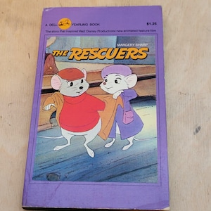May include: A purple paperback book with a cover image of two mice, one wearing a red jacket and the other wearing a purple jacket. The title of the book is "The Rescuers" and the author is Margery Sharp. The book is a Dell Yearling Book and the price is $1.25.