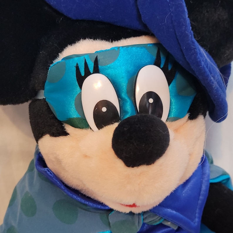 K&ouml;nnte beinhalten: Ein Pl&uuml;schtier von Mickey Mouse, das eine blaue und gr&uuml;n gemusterte Schlafmaske und einen blauen Mantel tr&auml;gt.