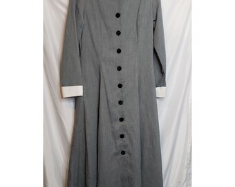 May include: A grey long-sleeved dress with a white collar and cuffs. The collar has black embroidered details. The dress has a button-up front with black buttons.