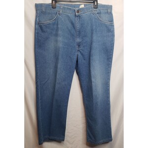 May include: A pair of blue denim jeans with a button fly and five pockets.