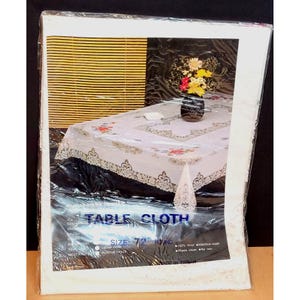 May include: White vinyl tablecloth with a lace trim and floral embroidery. The tablecloth is 72 inches in diameter and is machine washable.  The label reads "Table Cloth" and "Size: 72 Round".