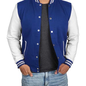 Può includere: Una giacca stile varsity blu reale con maniche bianche, colletto alla coreana con strisce bianche e bottoni a pressione argentati. La giacca presenta due tasche laterali con bordino bianco e polsini a coste con strisce bianche sopra una t-shirt grigia.