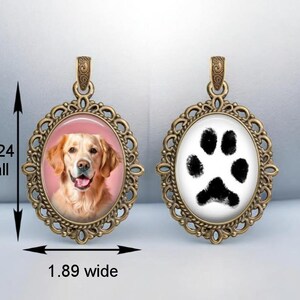 a pendant with a picture of a dog and a paw print, both encased in an ornate, gold-colored frame.
