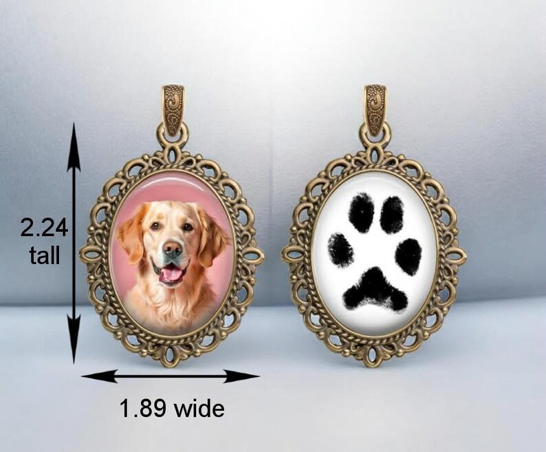 a pendant with a picture of a dog and a paw print, both encased in an ornate, gold-colored frame.