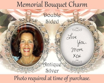 May include: A double-sided antique silver memorial bouquet charm featuring an oval frame with ornate filigree detailing. One side displays a photograph of a smiling person, while the other side features the handwritten text Love You. mom xox.