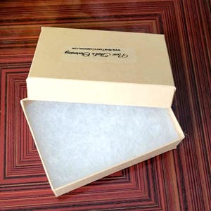a beige box with a white interior, placed on a wooden surface with a red and brown pattern.