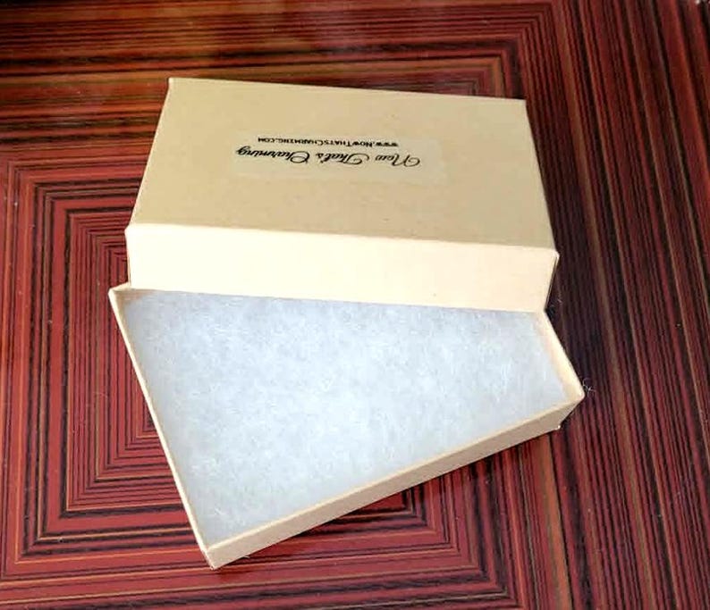 a beige box with a white interior, placed on a wooden surface with a red and brown pattern.