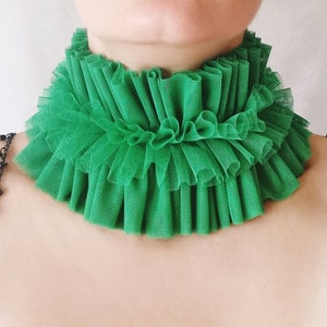 Może przedstawiać: Zielony choker z falbankami z tkaniny. Choker wykonany jest z miękkiej, przezroczystej tkaniny i ma delikatny, kobiecy wygląd.