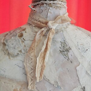 Peut inclure: Une bouteille en c&eacute;ramique blanche avec un ruban en dentelle nou&eacute; autour du cou. La bouteille est d&eacute;cor&eacute;e de couches de papier et a un aspect vieilli et vintage.