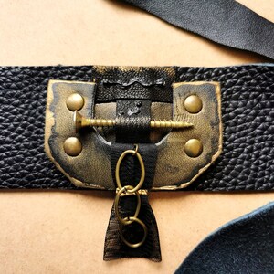 May include: Black leather bracelet with gold accents, a screw detail, and a chain charm.