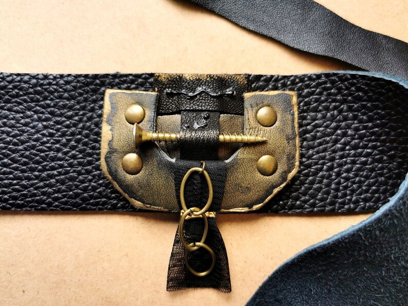 May include: Black leather bracelet with gold accents, a screw detail, and a chain charm.
