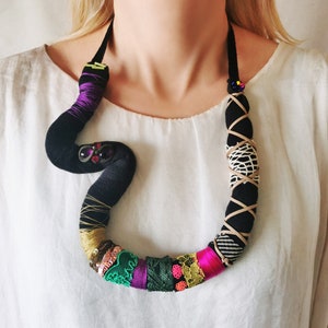 Schwarze röhrenförmige schlangenförmige Halskette mit bunter Textilcollage aus Spitze, Garn und Pailletten, asymmetrische herausragende eklektische Stoffhalskette Bild 1