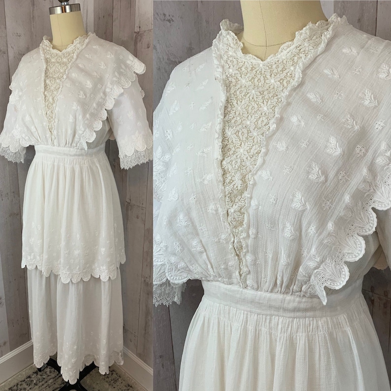 May include: A white cotton dress with a lace overlay and scalloped edges. The dress has a fitted bodice and a full skirt. It is a vintage style dress.