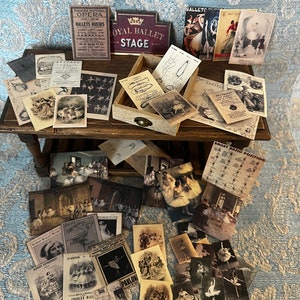 Peut inclure: Une collection d'éphémères de ballet vintage, comprenant des affiches, des programmes et des photographies. Les articles sont disposés sur une table en bois avec un tiroir. Les éphémères présentent des images de danseurs dans diverses poses, ainsi que du texte sur la compagnie de ballet et les spectacles. Le texte comprend les mots "Royal Ballet Stage", "Ballets Russes", "Carnaval" et "Pavlov".