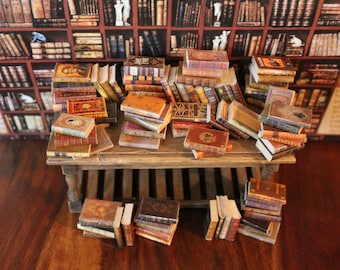 May include: A collection of miniature books stacked on a wooden table. The books are all different sizes and have brown leather covers with gold lettering. The books are arranged in a random pattern, creating a visually appealing display.