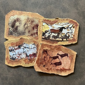 May include: Four brown paper squares with images of cave paintings. The images include handprints, a bull, and deer.