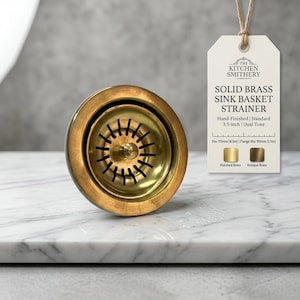 May include: A solid brass sink basket strainer with a dual tone finish. A tag attached by twine displays the text: THE KITCHEN SMITHERY, SOLID BRASS SINK BASKET STRAINER, Hand-Finished, Standard 3.5-inch, Dual Tone, Dia: 115mm (4.5in), Flange Dia: 90mm (3.5in).