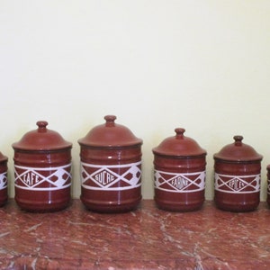 May include: Set of six red ceramic canisters with white lids and white lettering. The canisters are labeled "POIVRE", "CAFE", "SUCRE", "FARINE", "EPICES", and "THE".