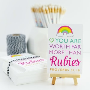 May include: A white card with a rainbow, clouds, and the text "You are worth far more than rubies Proverbs 31:10" on a small wooden easel.