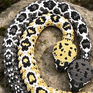 May include: A coiled snake sculpture featuring a textured, scale-like surface. The body displays a pattern of black, white, and yellow segments. One head is primarily yellow with black spots, while the other head is dark gray with black markings.