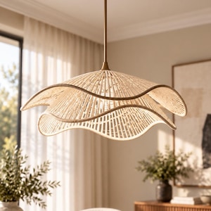 May include: A pendant light fixture featuring a wide, double-layered shade crafted from light-colored woven rattan. The shade has a distinct wavy, scalloped edge and is suspended from the ceiling by a thin, straight, metallic bronze-toned rod.