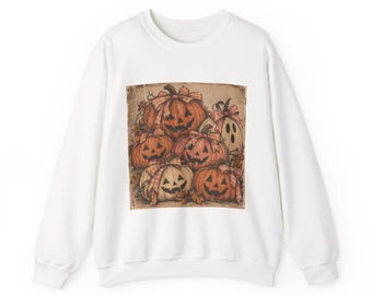 May include: A white long-sleeve crewneck sweatshirt featuring a central graphic print of several orange and cream-colored pumpkins with carved jack-o'-lantern faces, each adorned with a small plaid ribbon bow, set against a textured tan background.