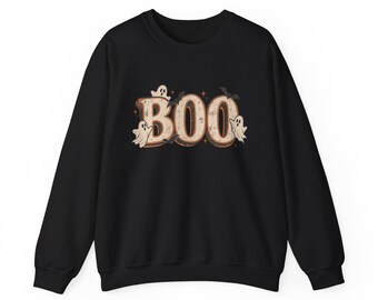 May include: A black long-sleeve sweatshirt featuring the word BOO in large, beige, distressed-style letters. The design is decorated with small white ghost illustrations, tiny black bats, and small star accents centered on the chest area.