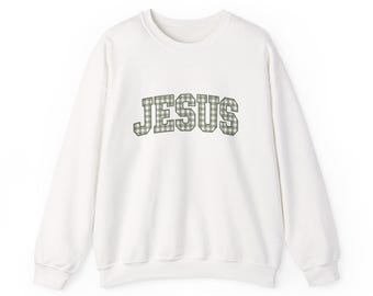 May include: A white long-sleeve crewneck sweatshirt featuring the word JESUS printed in a sage green and white gingham check pattern across the chest. The lettering is styled in a bold, arched collegiate font with a solid dark outline.