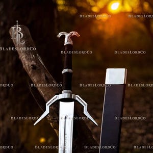 May include: A silver-toned metal sword featuring a dark handle with a dual-animal head pommel, a crossguard with pointed quillons, and a matching dark scabbard with a silver-toned metal tip. The blade displays engraved text near the hilt.
