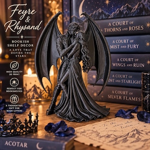 Op de afbeelding: Een zwart 3D-geprint beeldje van twee omhelzende figuren met grote vleugels, geplaatst voor een stapel boeken met de titels A Court of Thorns and Roses, A Court of Mist and Fury, A Court of Wings and Ruin, A Court of Frost and Starlight en A Court of Silver Flames.