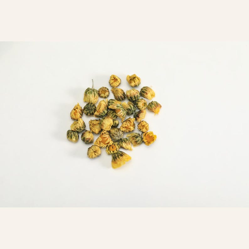 May include: A cluster of dried yellow chrysanthemum flowers. Each individual flower head is small, rounded, and tightly packed with golden-yellow petals, showing a slightly withered texture from the drying process, arranged in a loose pile.