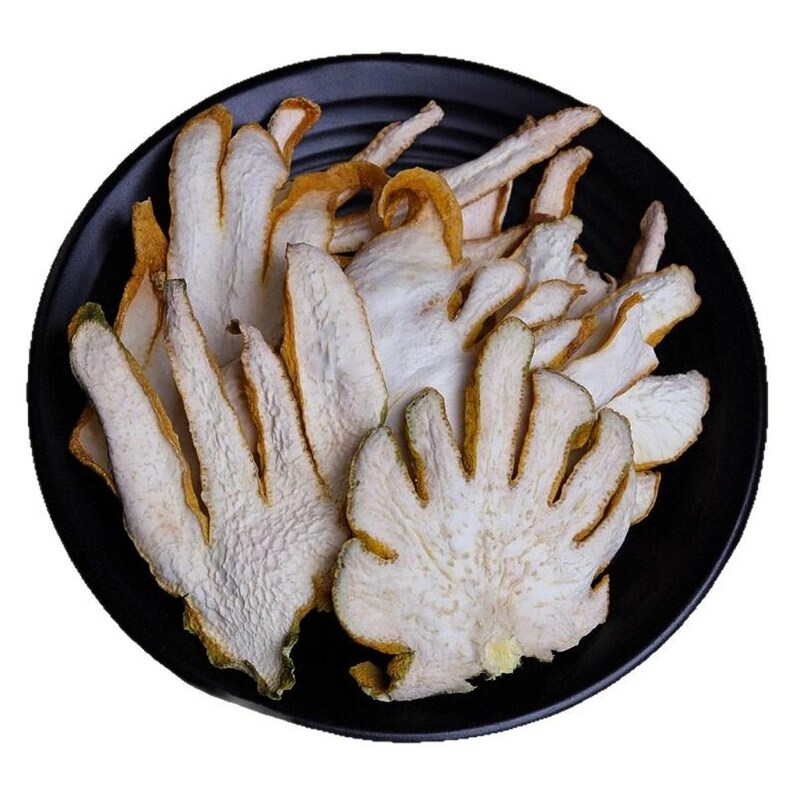 May include: A collection of dried, sliced Buddha's hand citron fruit pieces arranged on a round, black plate. The slices feature a textured, white interior flesh with a thin, yellow-green rind, showcasing the distinct finger-like segments.