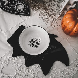 May include: A white ceramic bowl with a black bat design on the outside. The bowl has a black and white graphic that says "It's just a bunch of Hocus Pocus".