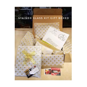 Puede incluir: Un kit de vidrieras presentado en una caja de cart&oacute;n marr&oacute;n con papel de seda de lunares dorados. El kit incluye una hoja de patrones impresa, un art&iacute;culo envuelto con un lazo dorado y dos tarjetas peque&ntilde;as con texto e im&aacute;genes de vidrieras.