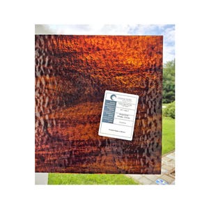 May include: A sheet of brown and orange textured glass with a label that reads "Oceanside Glass & Tile" and "Strawberry Granite".