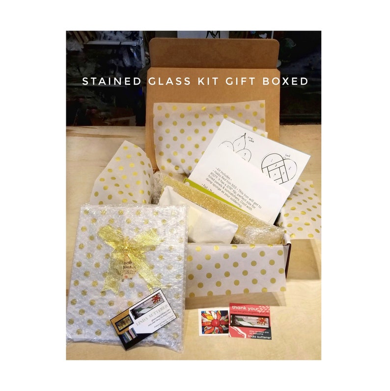 Puede incluir: Un kit de vidrieras presentado en una caja de cart&oacute;n marr&oacute;n con papel de seda de lunares dorados. El kit incluye una hoja de patrones impresa, un art&iacute;culo envuelto con un lazo dorado y dos tarjetas peque&ntilde;as con texto e im&aacute;genes de vidrieras.