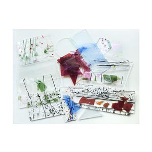 May include: Assortment of colorful glass pieces with abstract designs and black lines. The pieces are arranged on a white surface.