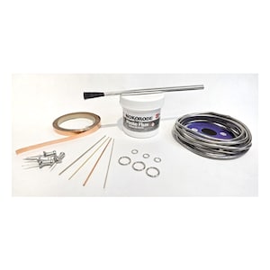 Puede incluir: Un kit de soldadura que contiene un recipiente blanco de pasta de fundente Nokorode, un cepillo de metal, un rollo de cinta de cobre, una bobina de hilo de soldar plateado, cuatro pasadores de metal, cuatro varillas finas y tres anillas plateadas.