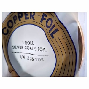 May include: A roll of 1/4 inch by 36 yard silver coated copper foil. The foil is wrapped around a cardboard core with a label that says "Copper Foil" in a blue circle with gold stripes.