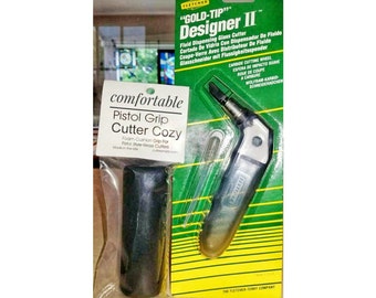 May include: A green and yellow package with a silver glass cutter and a black foam cushion grip. The package says "Gold-Tip Designer II" and "Comfortable Pistol Grip Cutter Cozy".