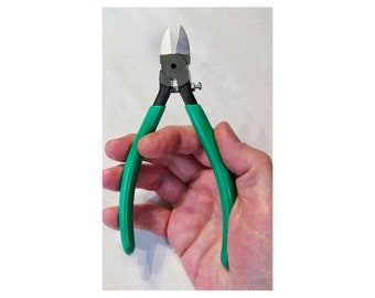 May include: Green handled wire cutters with a black metal head and a spring.
