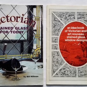 May include: Two books about stained glass window designs. The book on the left is titled "Victorian Stained Glass For Today" and features a colorful stained glass window design. The book on the right is titled "An idea book of Victorian and art nouveau stained glass window designs".