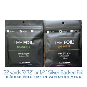 May include: Two black foil cassette packages with silver foil. One package reads "1/4" | 22 yds. 6,4mm | 20m" and the other reads "7/32" | 22 yds. 5,7mm | 20m". The text "THE FOIL CASSETTE" is printed on both packages.
