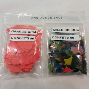 May include: Two clear plastic bags containing one ounce bags of confetti. The bag on the left contains orange opal confetti. The bag on the right contains mixed colors of confetti. Both bags have labels that say "Confetti 90".